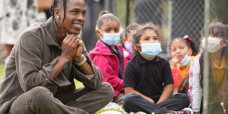 Houston native Travis Scott listens to his sister, Jordan Webster, read a book about gardening during the ribbon cutting ceremony for the Cactus Jack Garden at Ethel M. Young Elementary School in Houston on Wednesday, Nov. 3, 2021.