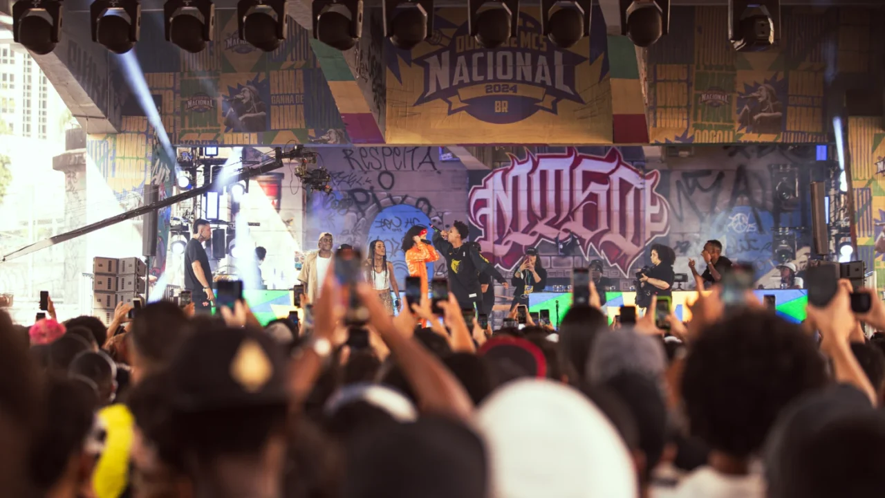 Duelo de MCs Nacional 2025 reúne artistas de todo o país neste fim de semana em BH 1 MCs batalhando no palco do Duelo de MCs Nacional 2025 em BH, com a plateia animada.